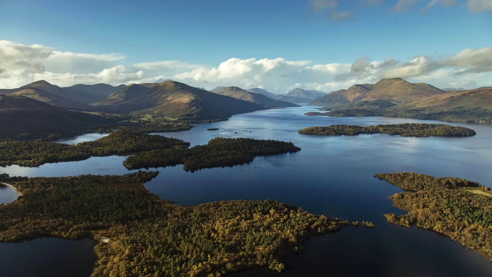 Aerial view of Loch Lomond's wooded islands with hills rising behind the loch